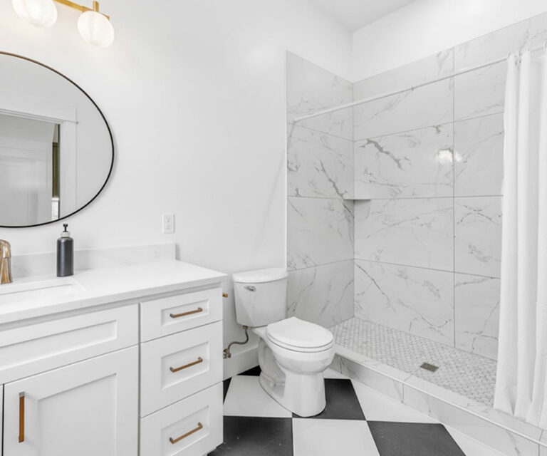 NE Portland remodeled bathroom with porcelain tile, hexagon floor, tile shower, quartz vanity, gold hardware, new toilet, and lighting